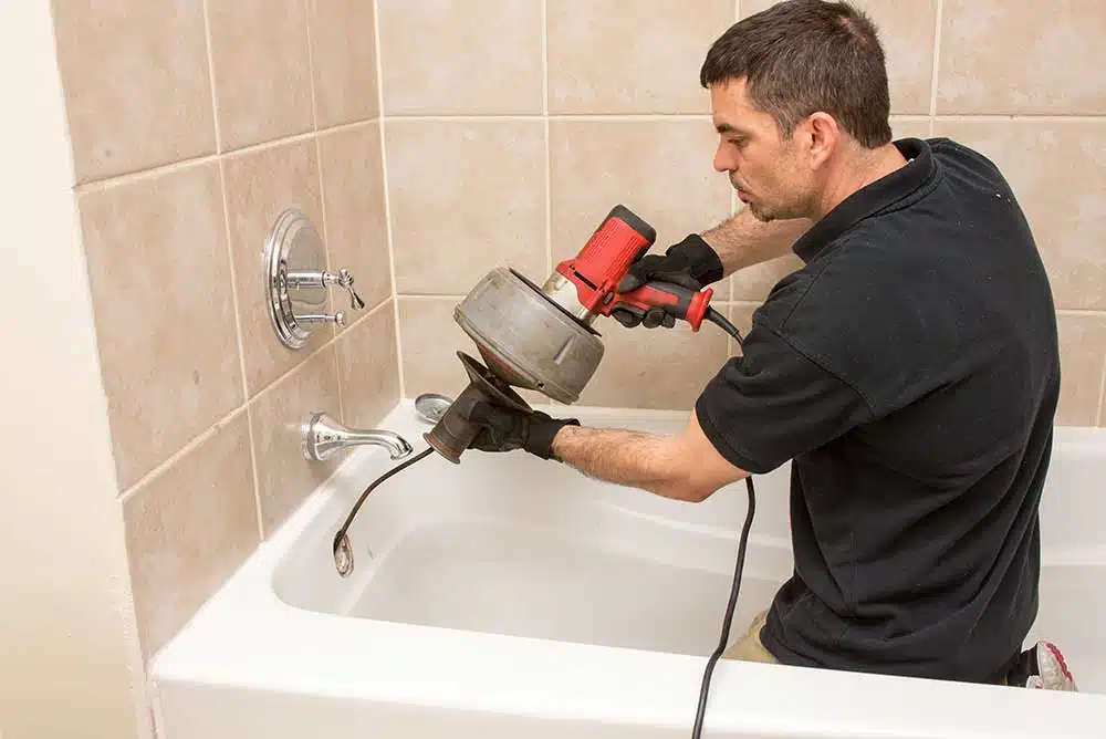 a person snaking to fix a bathtub
